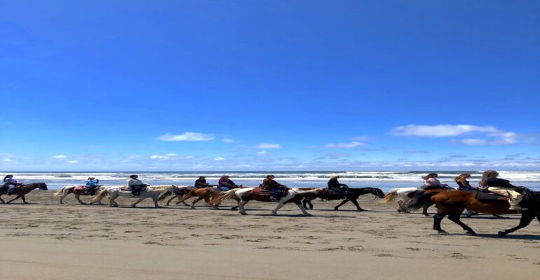 Group of riders on horseback along the Pacific Ocean beach in Ocean Shores, Washington
