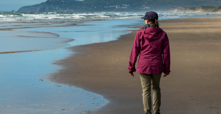 Woman in rain jacket walking along the Washington coast beach